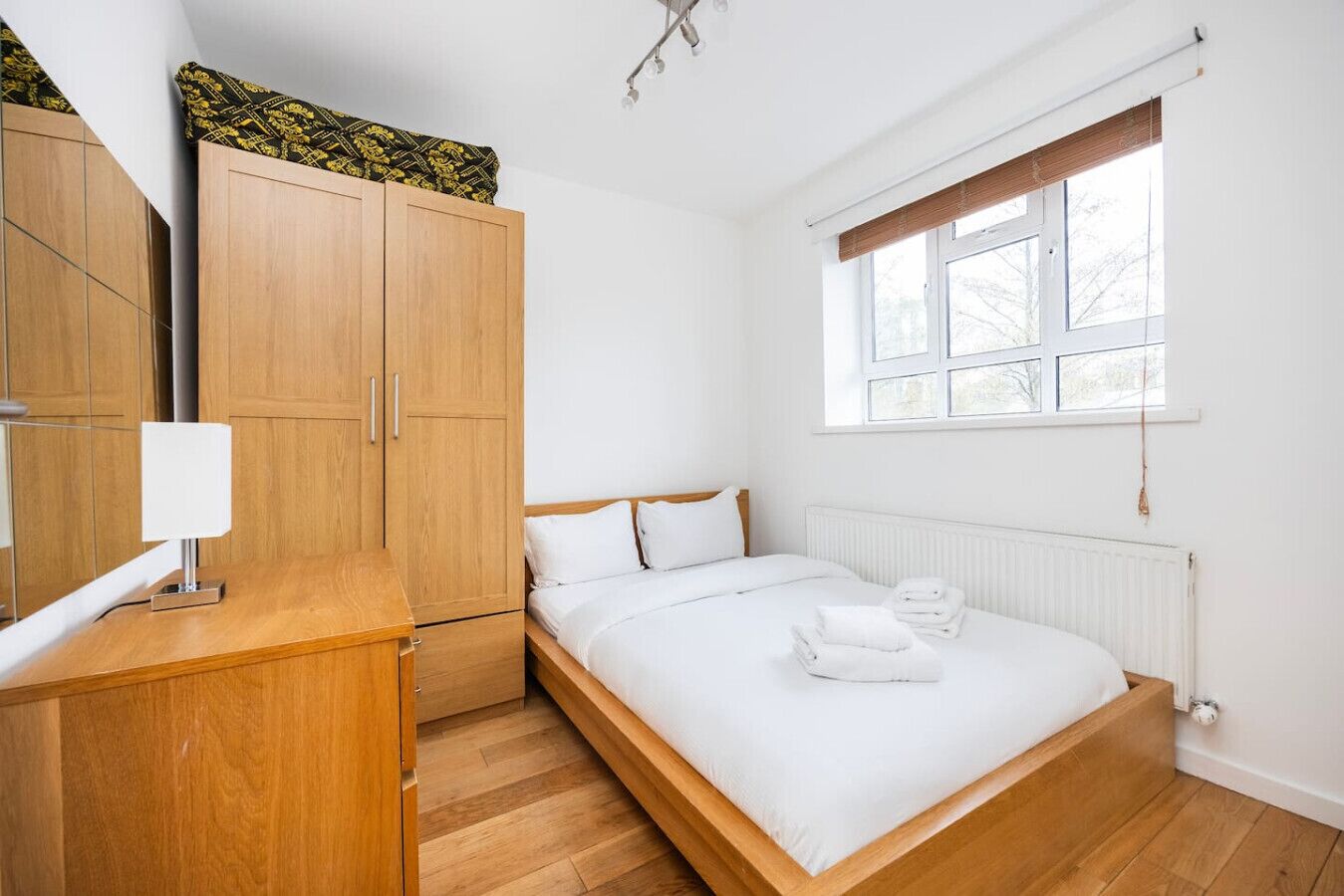 Una camera da letto con un letto, un armadio in legno e una finestra con persiane.