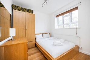 Quarto com cama, guarda-roupa de madeira e janela com persianas.