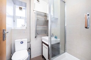 Ein Badezimmer mit Toilette, Waschbecken, Duschkabine und Handtuchhalter.