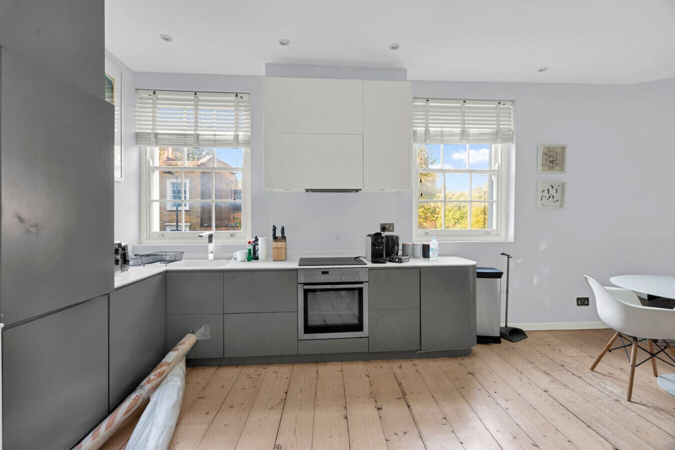 A modern kitchen with grey cabinets, a built-in oven, and a central island.