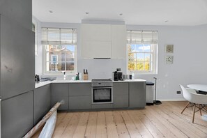Eine moderne Küche mit grauen Schränken, einem eingebauten Backofen und einer Kochinsel.