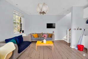 Ein Wohnzimmer mit einer Couch, einem Couchtisch, einem Fernseher und einer Treppe.