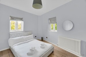 A bedroom with a bed, two windows, a radiator, and a round mirror. - 2BR Central London Stay in King’s Cross -Sleeps 4 (Greater London)