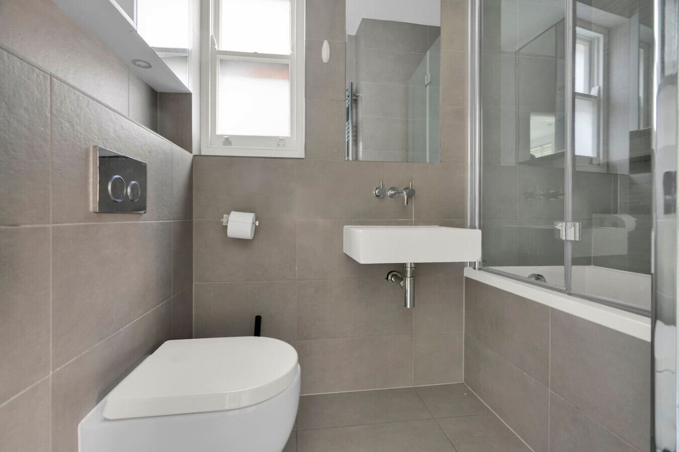 Ein modernes Badezimmer mit Toilette, Waschbecken und Dusche.