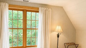 Ein Schlafzimmer mit großem Fenster, Lampe, Bett und Teppich.