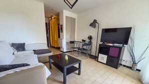 A living room with a sofa, coffee table, TV, and a desk with a chair. - Studio cabin in Cap d'Agde, parking - 2 guests (Cap d'Agde)