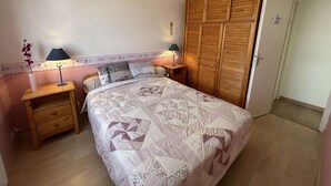 A bedroom with a bed, two bedside tables, a nightstand, a wardrobe, and a door. - Apartment sea view - 4 guests (Saint-Jean-de-Monts)