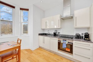 Eine moderne Küche mit weißen Schränken, einer Granitabdeckung, einem eingebauten Backofen und einer Kaffeemaschine.