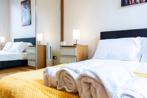 Et hotelværelse med en seng, sengeborde, et spejl og et kunstværk på væggen.