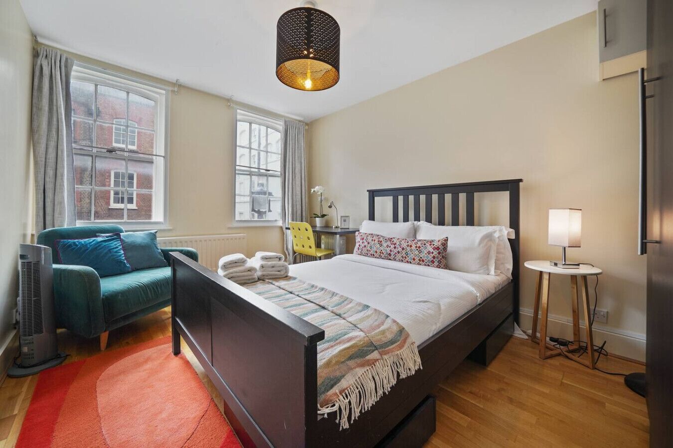 A bedroom with a bed, a chair, a lamp, and a heater.