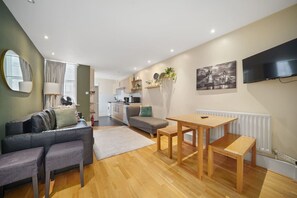 A modern living room with a sofa, a dining table, and a kitchen in the background. - 2-BR in the Heart of Soho - 5 guests (Greater London)