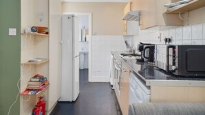 A compact kitchen with a refrigerator, microwave, stove, and a small sink area. - 2-BR in the Heart of Soho - 5 guests (Greater London)