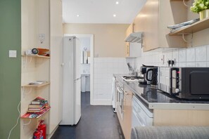 A compact kitchen with a refrigerator, microwave, stove, and a small sink area. - 2-BR in the Heart of Soho - 5 guests (Greater London)