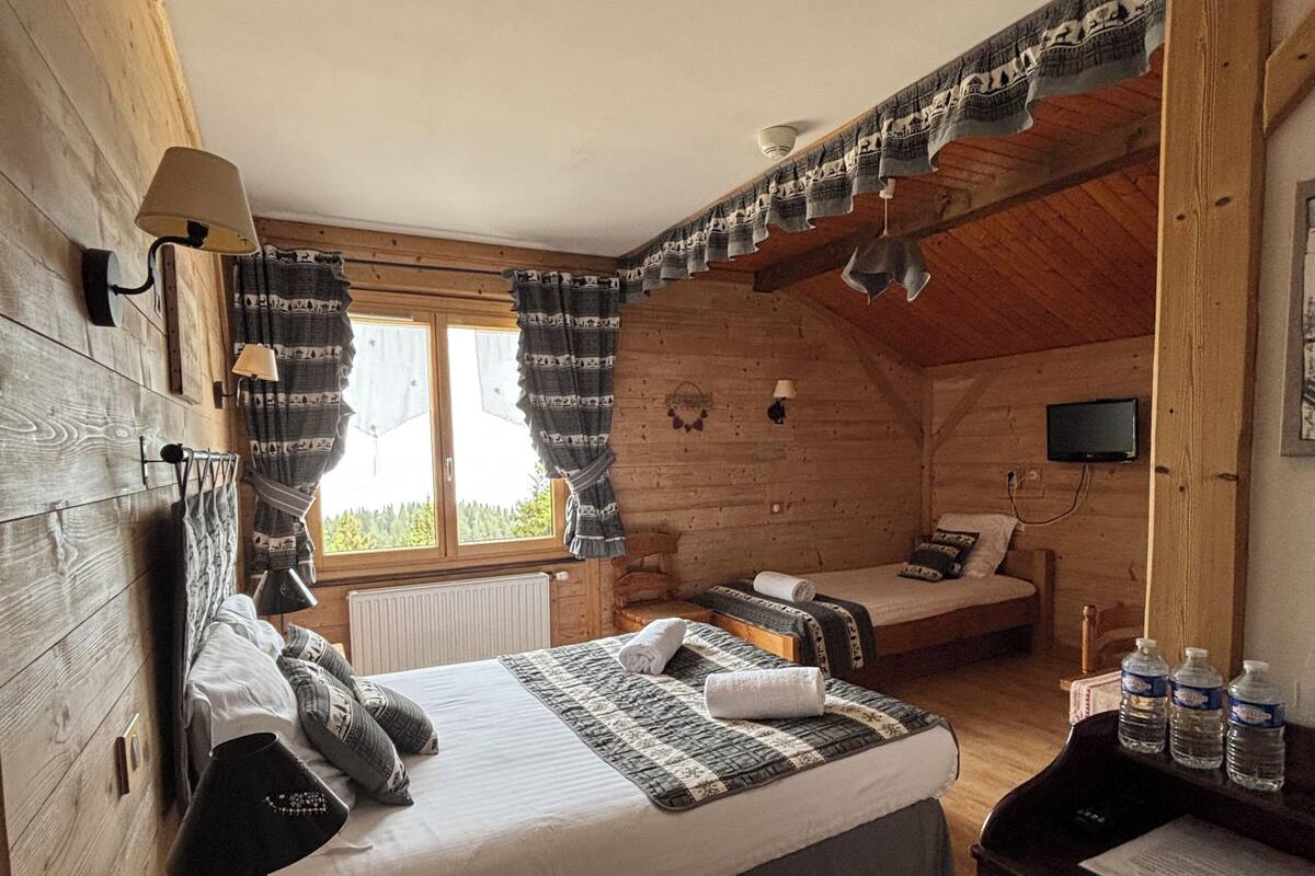 A log cabin bedroom with a bed, bedside lamps, a desk, and a chair.