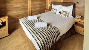Una habitación con paneles de madera, una cama, mesitas de noche, un lámpara colgante y una decoración de pared con forma de estrella.