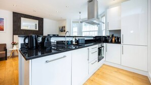 A modern kitchen with white cabinets, a black countertop, and a built-in oven. - 2BR Kensington| Walk to High St & Tube | Sleeps 6 (Greater London)