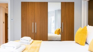 A hotel room with a bed, a wardrobe, and a window. - 2BR Kensington| Walk to High St & Tube | Sleeps 6 (Greater London)