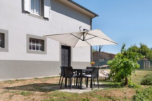 A patio with a table and chairs, an umbrella, and a potted plant.