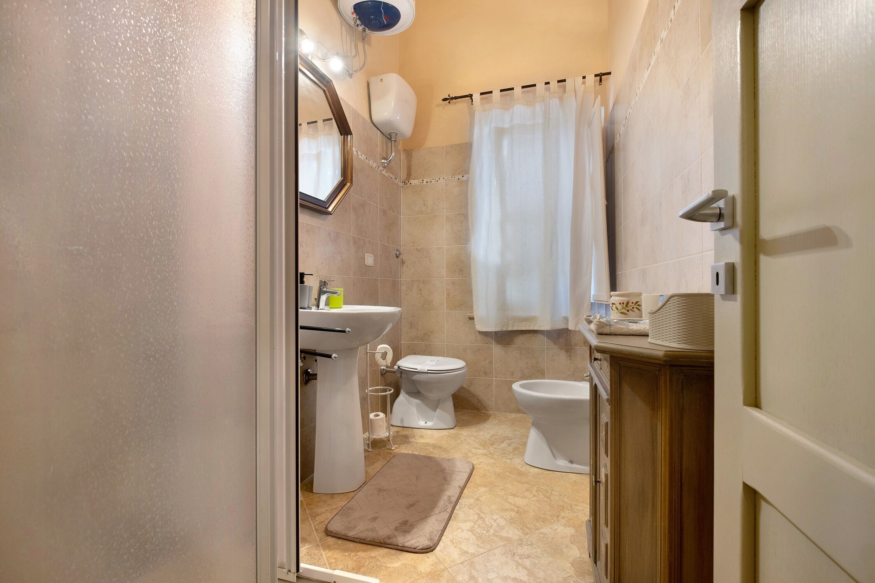 Un bagno con il water, un bidet, un lavandino e una tenda per la doccia.