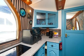 A compact kitchen with blue cabinets, a built-in stove, and a window providing a view.