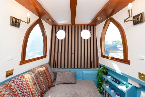 A cozy room with a bed, a window, and a wall-mounted shelf with books and plants.