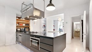Una cocina moderna con una isla central, horno integrado y electrodomésticos de acero inoxidable.