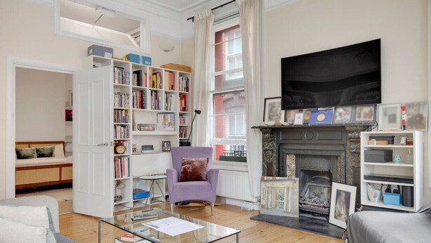 Ein Wohnzimmer mit Kamin, Bücherregalen, einer Couch und einem Couchtisch.