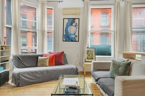 A living room with a grey sofa, a glass coffee table, and a bookshelf. - 1 Bedroom Apartment in Central Soho - 4 people (Greater London)