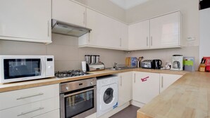 Eine moderne Küche mit Mikrowelle, Gasherd, Toaster und Waschmaschine.