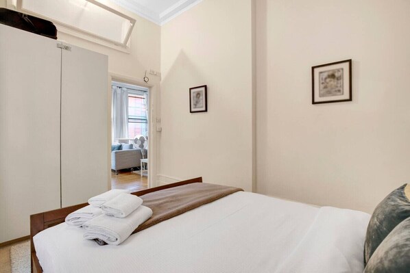 Quarto de hotel com uma cama, um guarda-roupa e vista para o corredor.