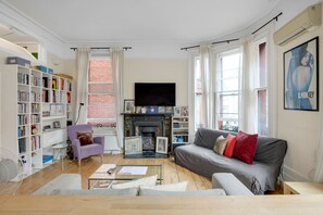A living room with a fireplace, a sofa, a bookshelf, and a television. - 1 Bedroom Apartment in Central Soho - 4 people (Greater London)