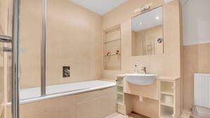 Ein modernes Badezimmer mit einer Duschkabine aus Glas, einem weißen Waschbecken und einem Spiegel darüber.