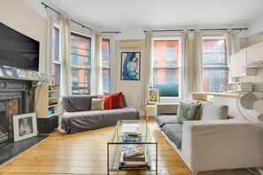 A living room with a fireplace, two sofas, a coffee table, and a fan. - 1 Bedroom Apartment in Central Soho - 4 people (Greater London)
