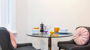 Een ronde glazen tafel met stoelen, een koffiezetapparaat en verschillende kopjes en kommen.