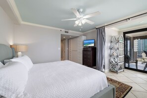 A hotel room with a bed, a ceiling fan, a television, a wardrobe, and a balcony with outdoor furniture. - Broadmoor 701 by Liquid Life (Orange Beach)
