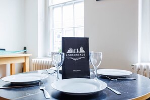 A table set for two with a black menu stand labeled 'LONDONPADS Welcome' and two empty wine glasses. - 1BR in Dean Street Central - 4 people (Greater London)