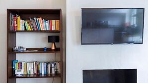 Kirjahylly täynnä kirjoja, lamppu ja televisio seinällä.