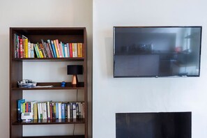 A bookshelf with books, a lamp, and a television on a wall. - 1BR in Dean Street Central - 4 people (Greater London)