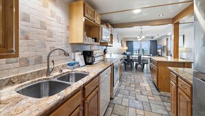 A kitchen with granite countertops, stainless steel appliances, wooden cabinets, and a tiled backsplash. - Castaways 1C by Liquid Life (Gulf Shores)