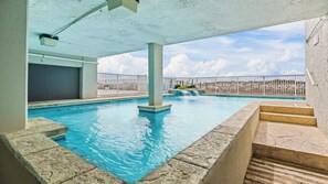 Una piscina interior con agua azul cristalina, un deck de hormigón y vista a un paisaje lejano.