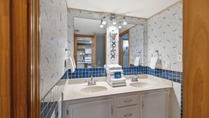 A bathroom with two sinks, a mirror, and a towel rack. - Castaways 1C by Liquid Life (Gulf Shores)