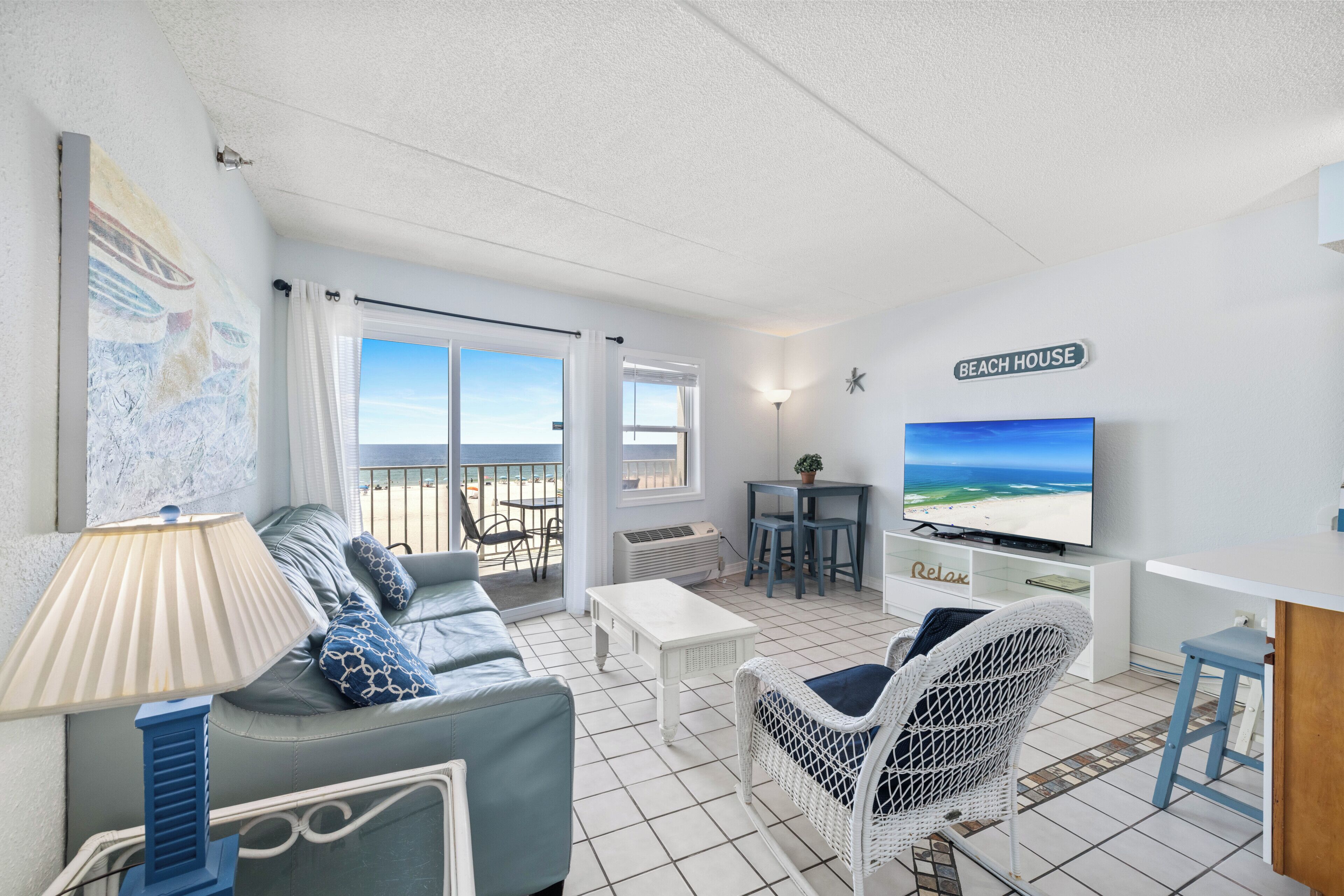 Un salon avec un canapé, un téléviseur et une vue sur la plage.