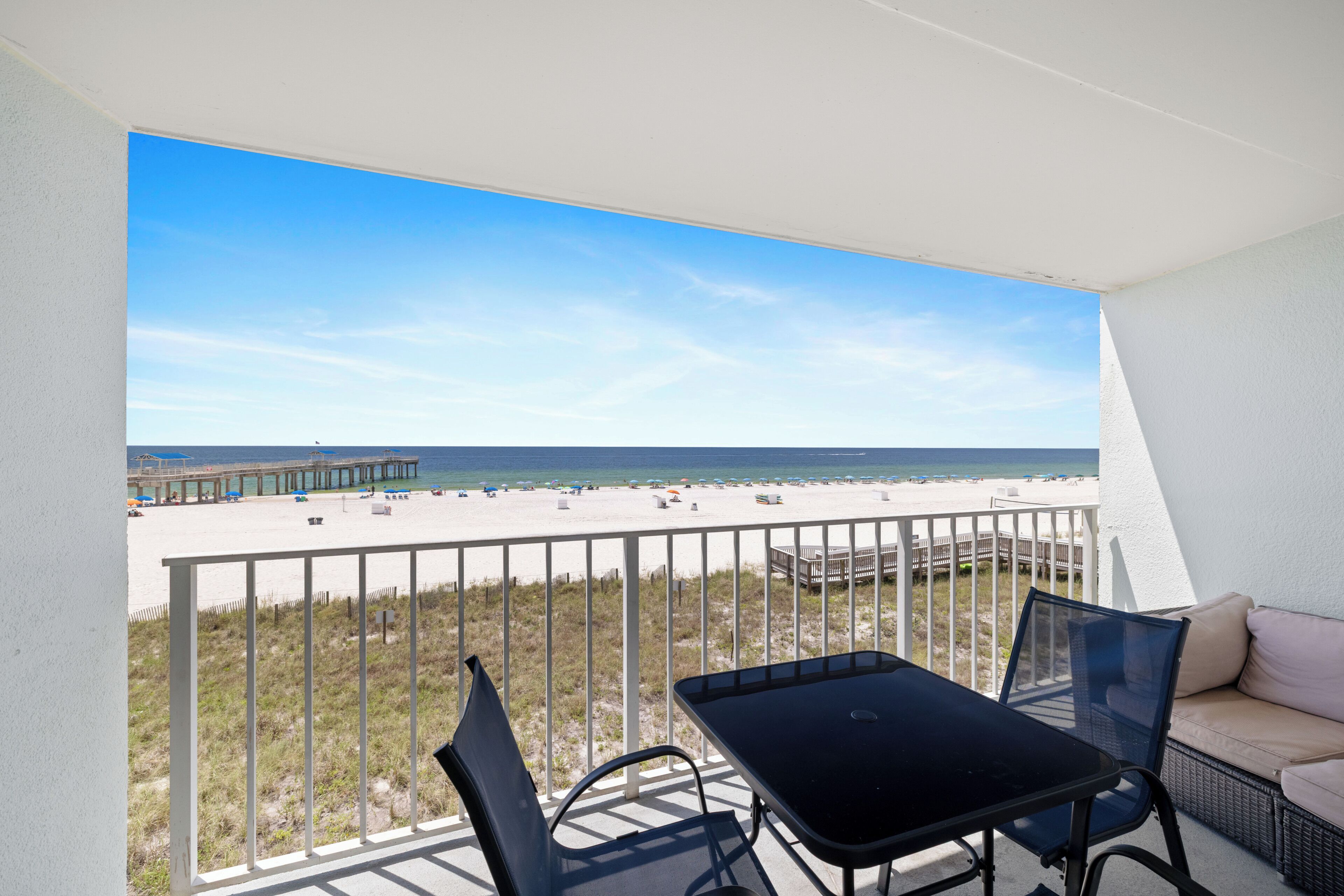 Un balcon avec vue sur une plage et une jetée.