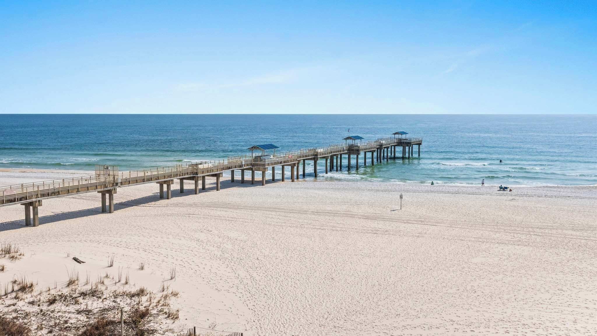 Ein Strand mit einer langen Seebrücke, die sich ins Meer erstreckt.