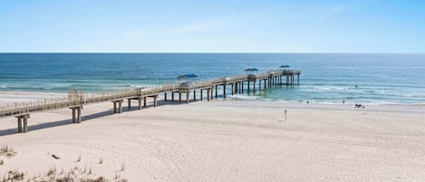 A beach with a long pier extending into the ocean.