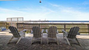 En terrasse med Adirondack-stole og udsigt til stranden.