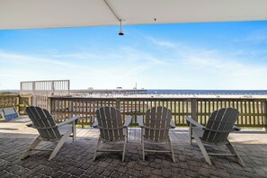 Eine Terrasse mit Adirondack-Stühlen und Blick auf den Strand.