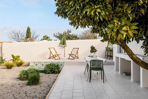A patio with two lounge chairs, a table, and a potted plant. - Refugio del Laurel, Sesimbra (Sesimbra)