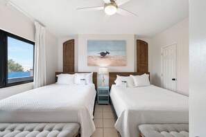 A hotel room with two beds, a ceiling fan, a painting, and a view of the outdoors. - Four Seasons 204W by Liquid Life (Orange Beach)