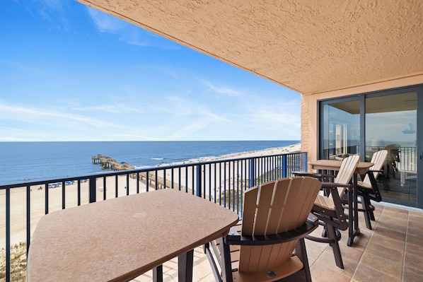 Uma varanda com vista para o oceano, com mesa e cadeiras.